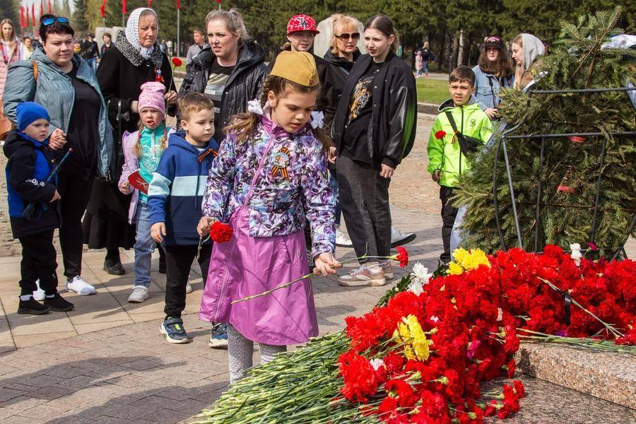 Омичи от мала до велика возлагают цветы к огню